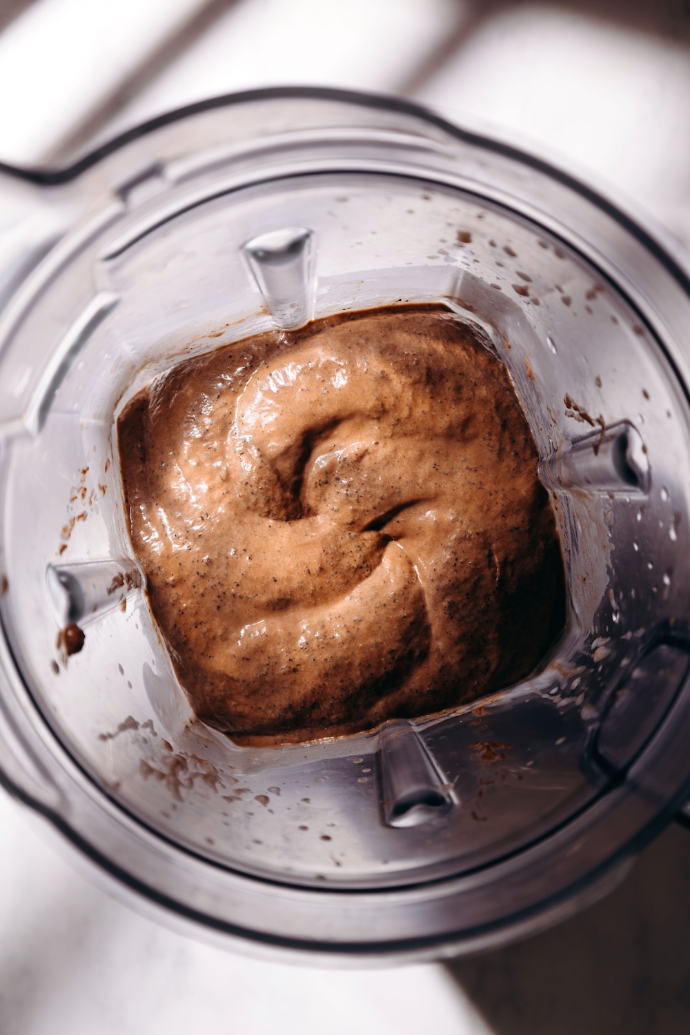 Overhead view of blended chocolate basil seed pudding in a high speed blender, showing a smooth, creamy mousse-like texture.