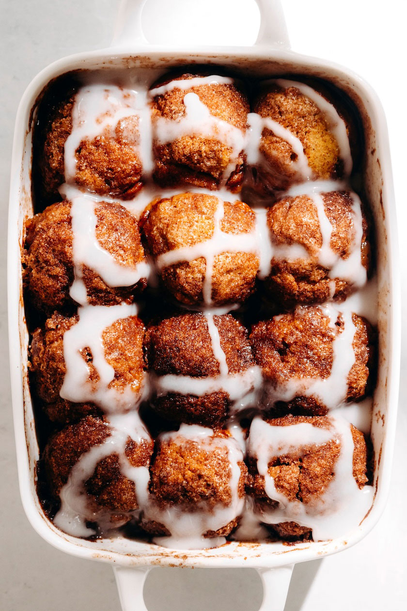 Overhead view of 12 glazed pumpkin cinnamon roll bites in a white baking dish.