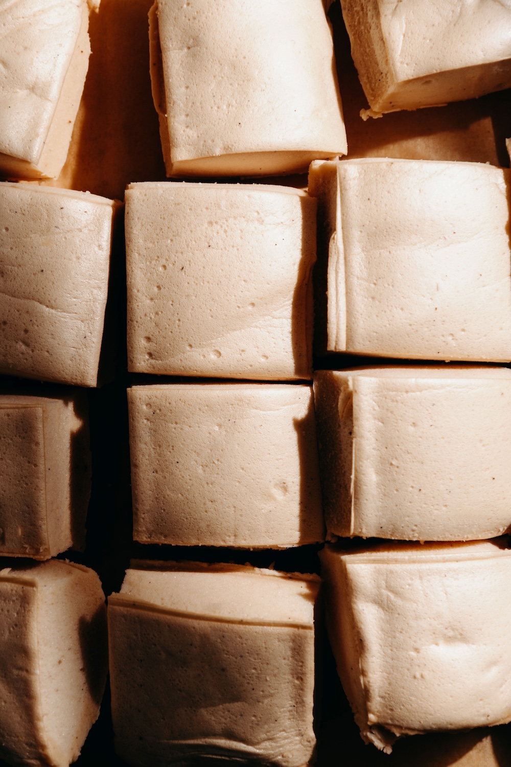 Sliced protein marshmallow squares on parchment paper before dipping in chocolate.