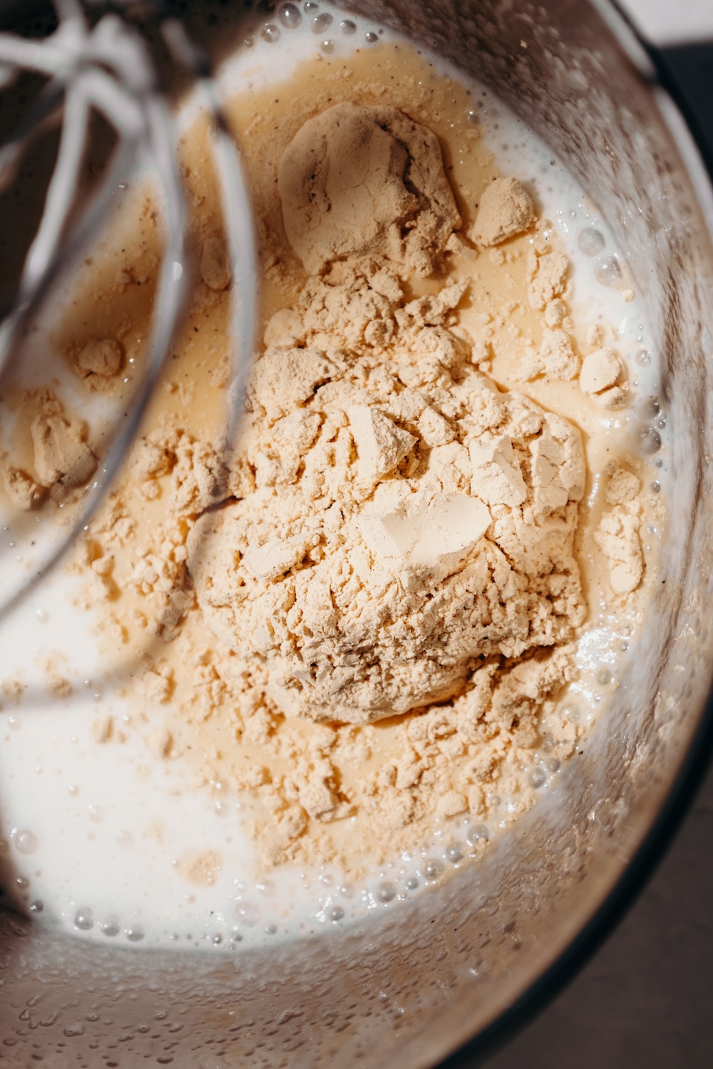 Vanilla protein powder added to the whipped gelatin mixture in a stand mixer bowl.